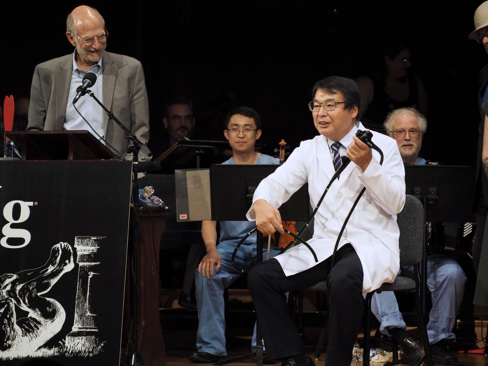 「イグ・ノーベル賞」の授賞式で、座った状態での大腸内視鏡検査を説明する堀内朗氏（右）＝2018年09月米ハーバード大学