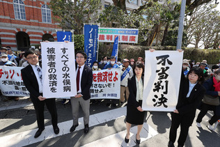 水俣病訴訟の判決を受け、「不当判決」などと書かれた紙を掲げる原告側弁護士＝２２日午前、熊本市中央区
