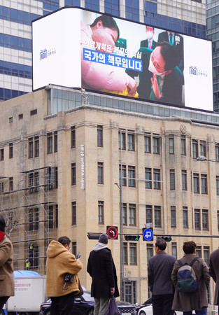 ソウルの街頭ビジョンで放映される韓国政府の医療改革に関する広報映像＝７日