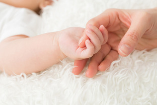 赤ちゃんと手をつなぐ女性（イメージ）