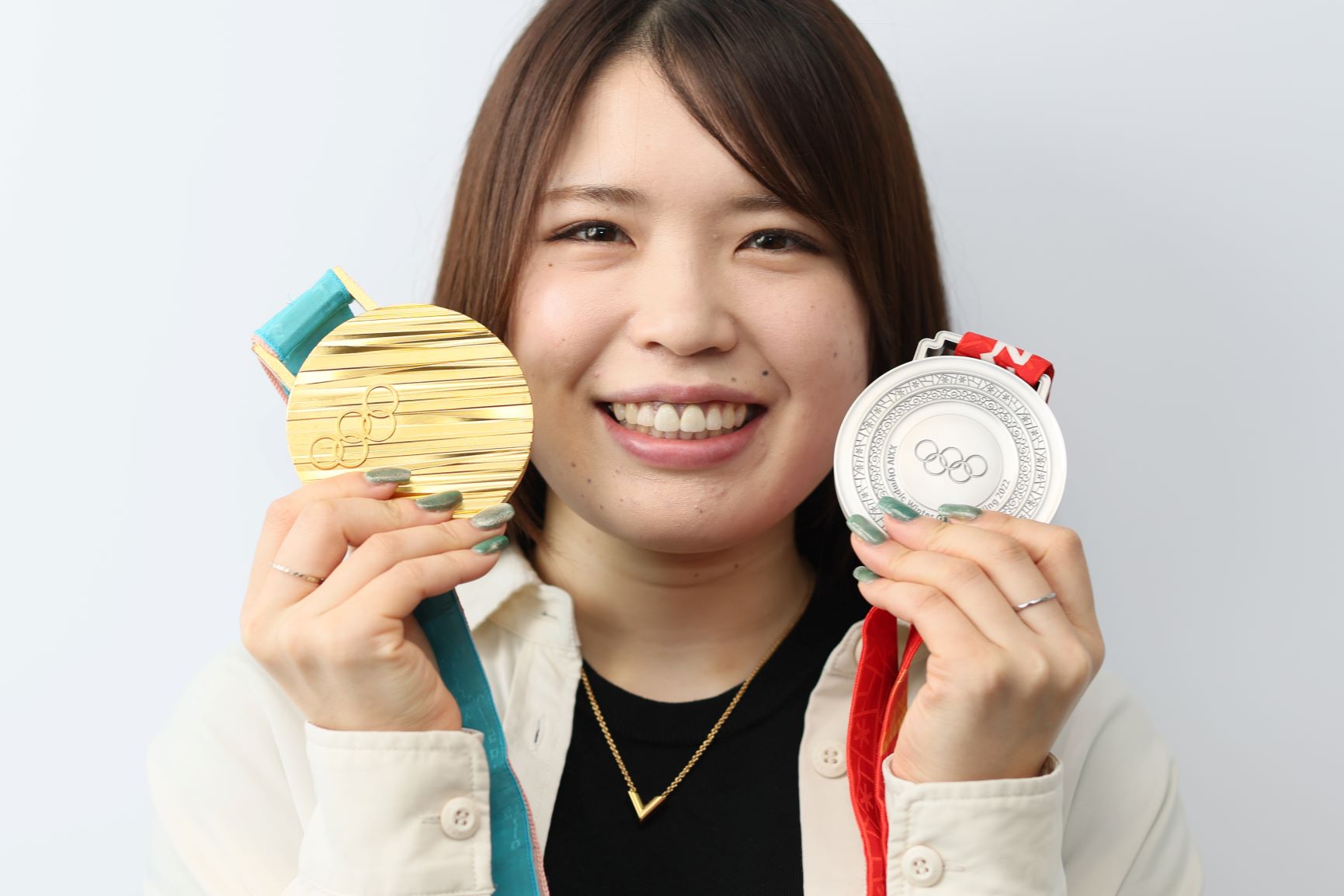 平昌五輪の金メダル（左）と北京五輪の銀メダルを持つ佐藤綾乃選手