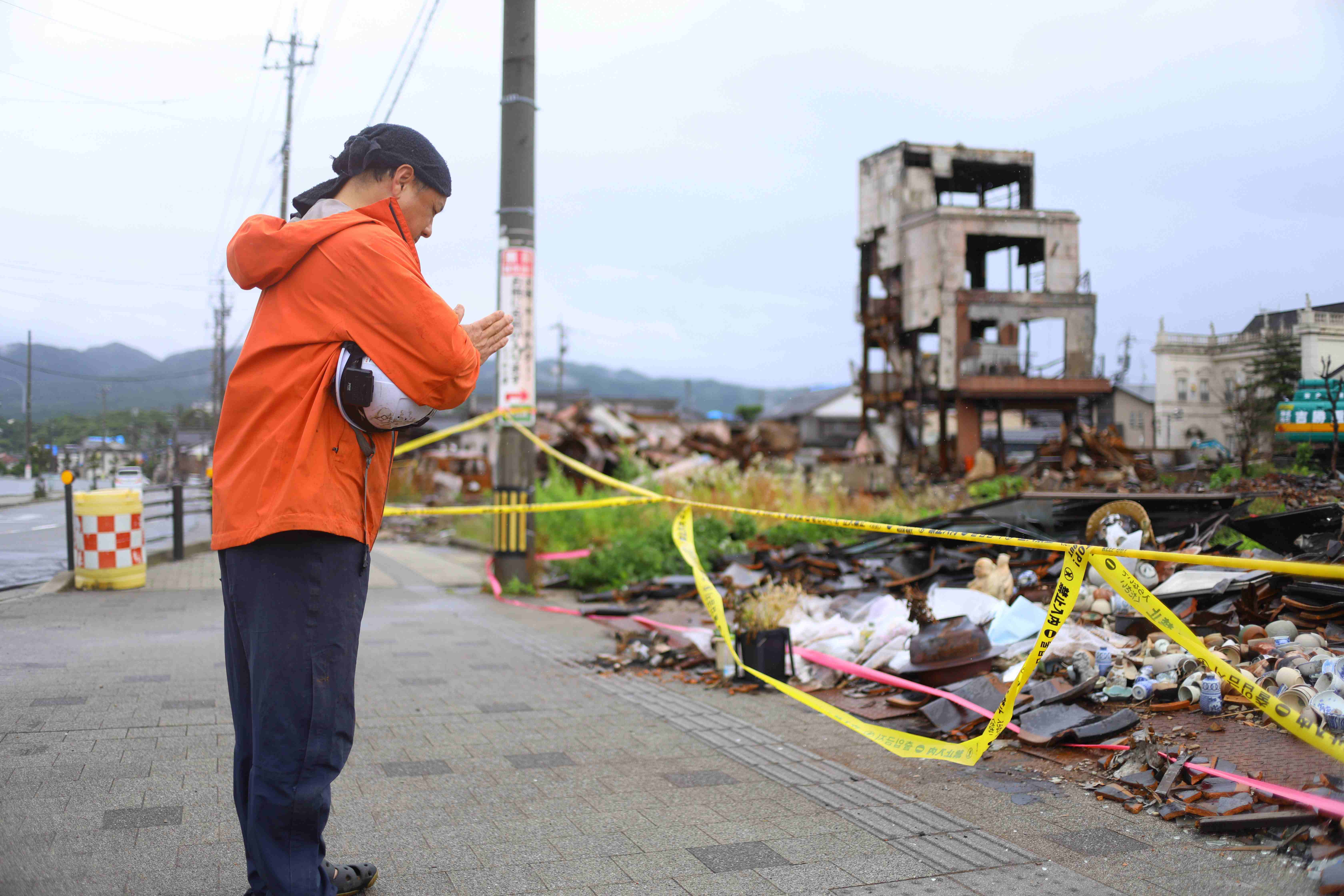 地震により焼失した朝市通り周辺で、手を合わせる人＝２０２４年６月３０日、石川県輪島市【時事通信社】