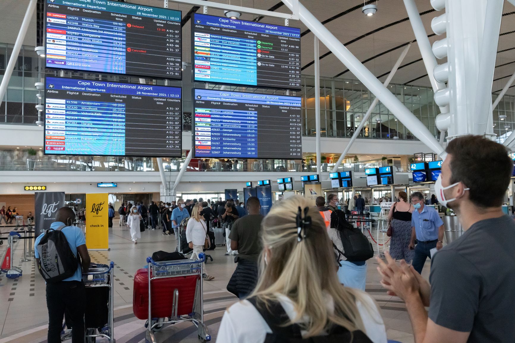 「オミクロン株」の確認を受けて各国の渡航制限が相次ぐ中、フライト情報の表示板を見詰める旅行者（南アフリカ・ケープタウンの空港）＝2021年11月28日＝EPA時事