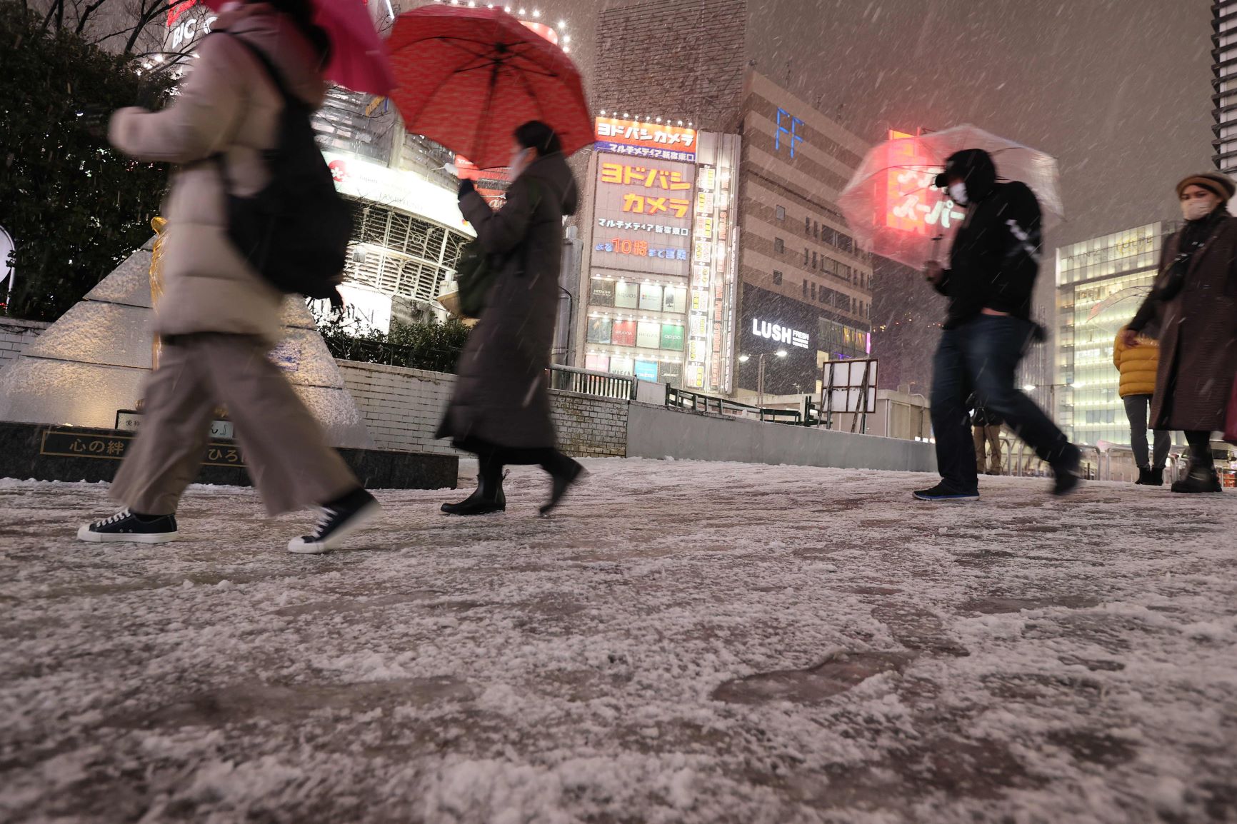 雪の中、ＪＲ新宿駅前を歩く人たち