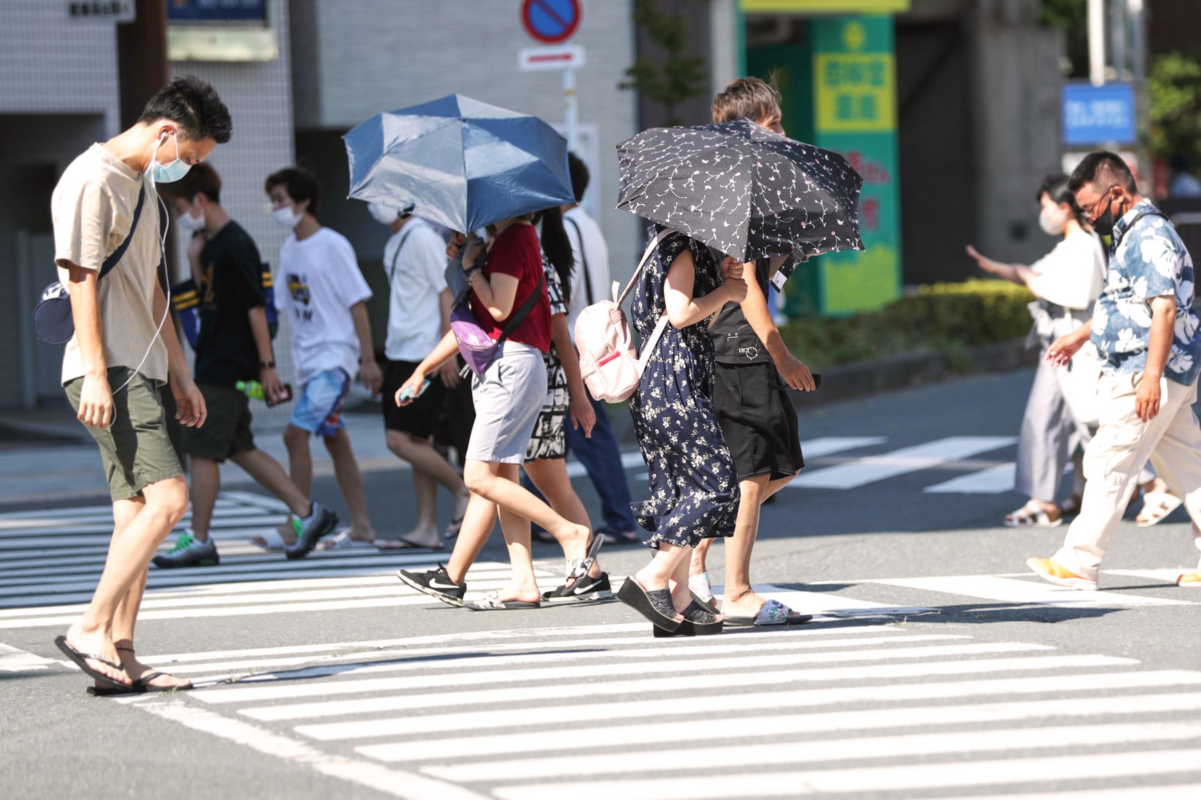 猛暑の中、日傘を差して歩く人たち＝2020年8月