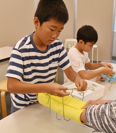 タオルを包帯代わりに使ってみるワークショップの参加者ら＝神戸市の「人と防災未来センター」