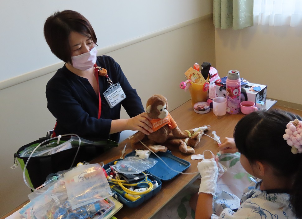 人形を使い小児患者に採血の疑似体験をさせる井上絵未さん＝済生会横浜市東部病院提供
