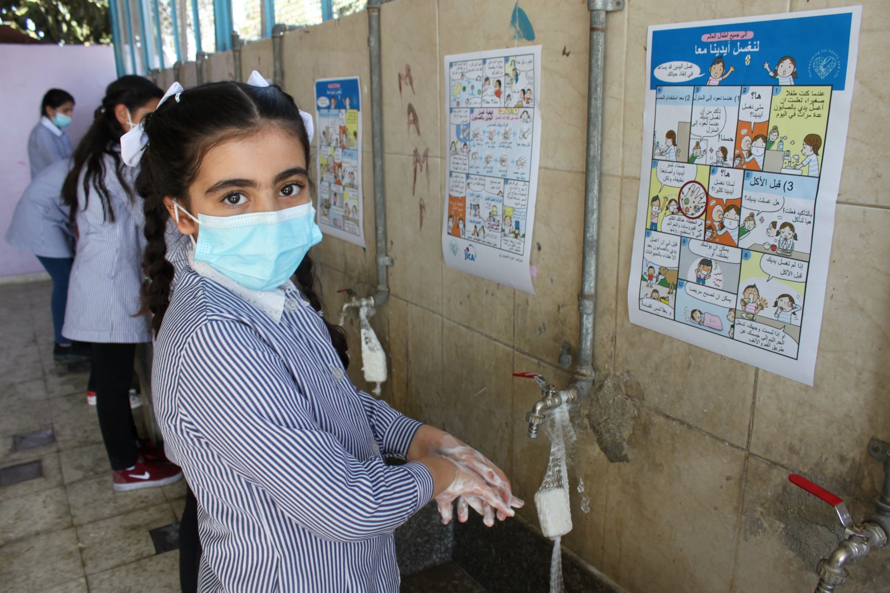 UNRWA（国連パレスチナ難民救済事業機関）の小学校で日本からの漫画（アラビア語版）を参考に手洗いする児童（ラマラの難民キャンプ・2020年10月撮影：JICA提供）