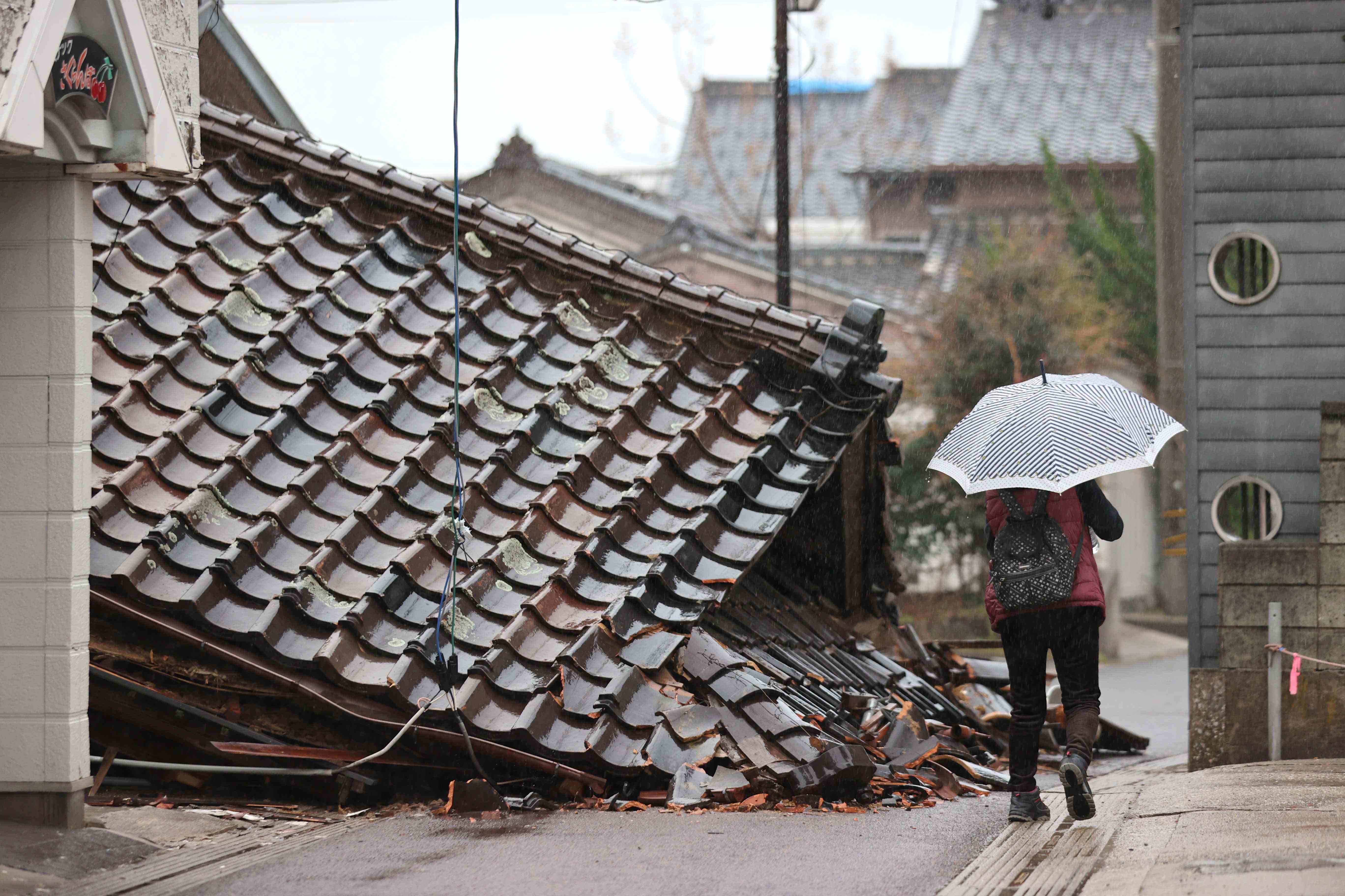 雨の中、被災地を歩く人（６日、石川県珠洲市）
