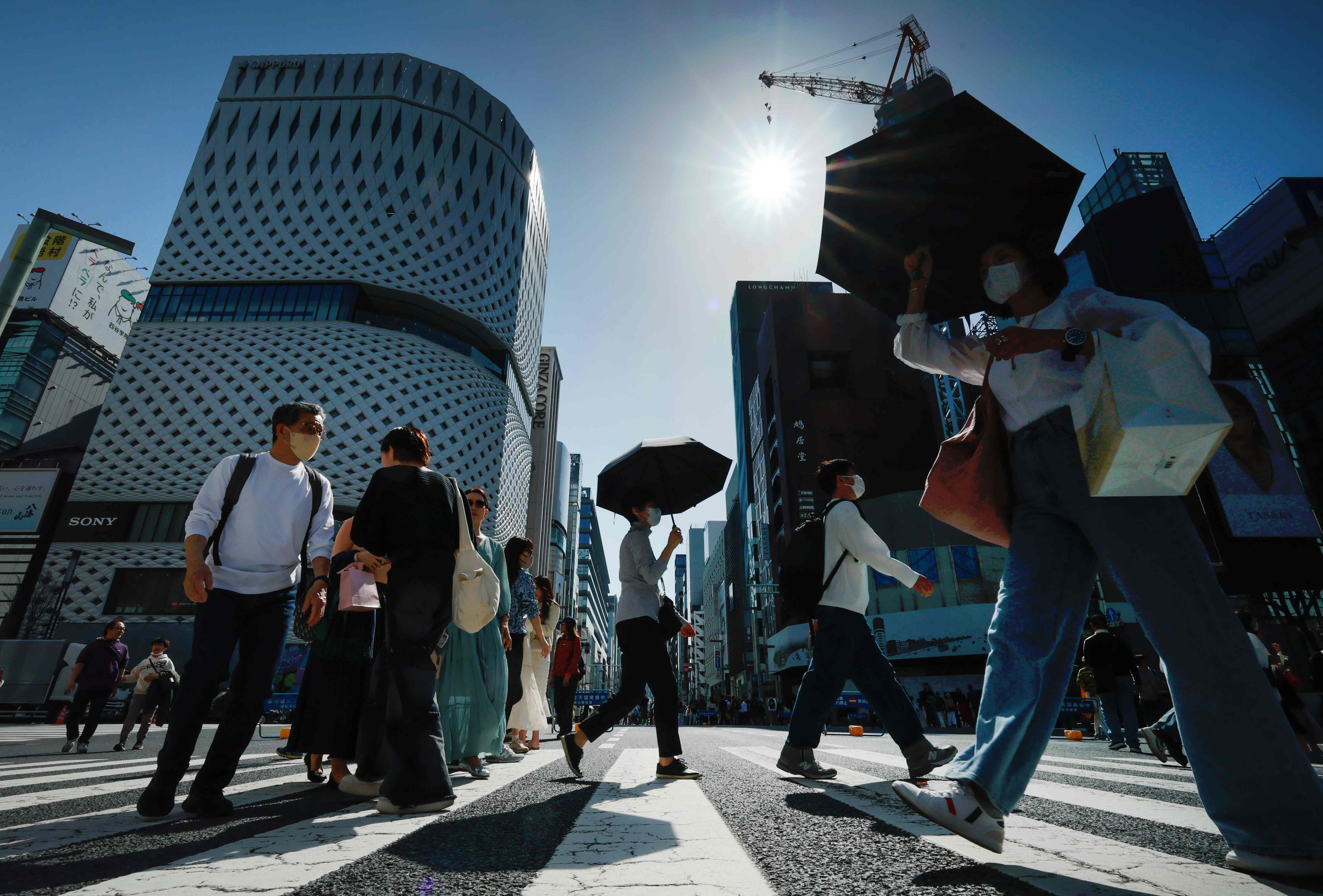 今年初めて夏日となり、傘を手に東京・銀座周辺を歩く人たち（３月３１日）