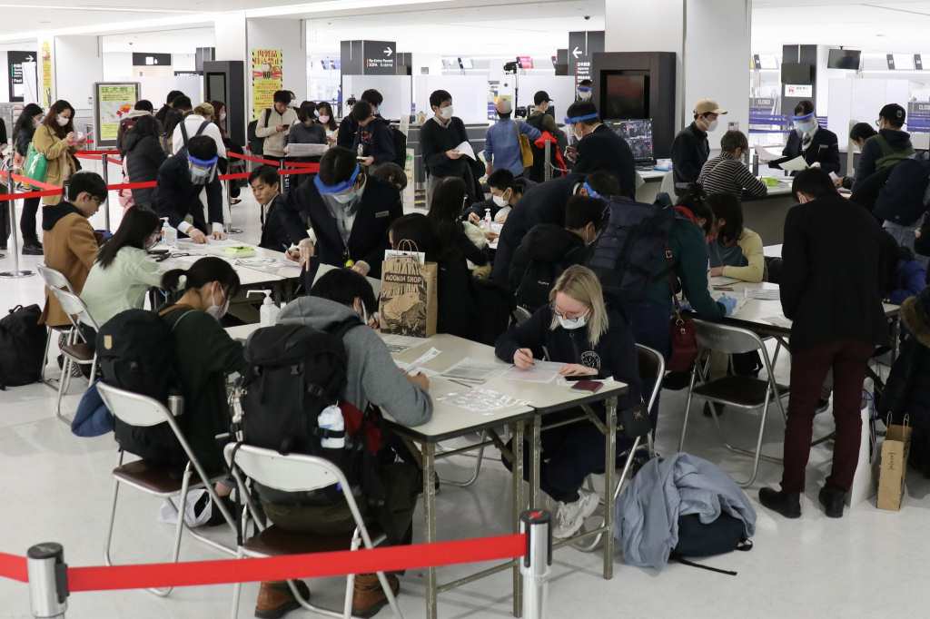 成田空港の検疫所で質問票に記入する乗客＝２０２０年３月