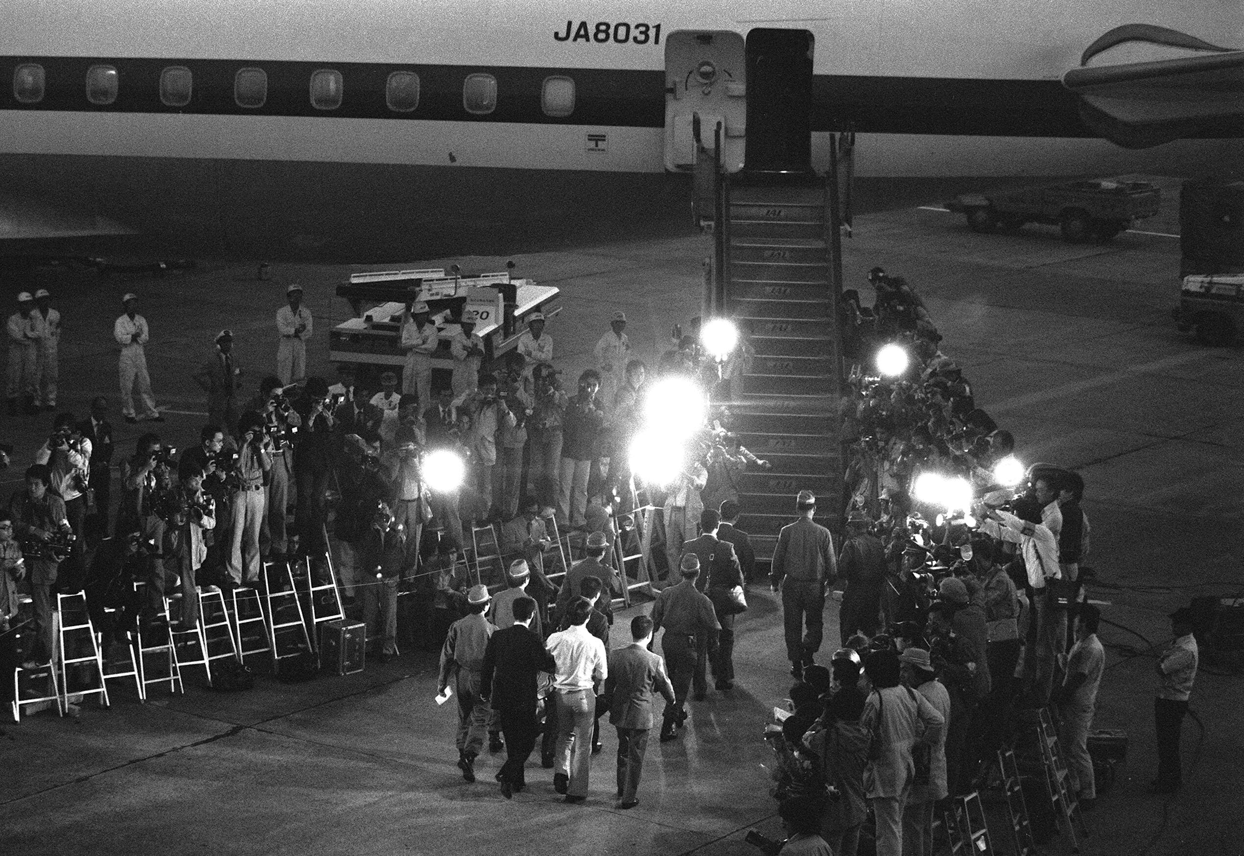報道陣が待ち構える中、次々と日航護送機に乗り込む６人の釈放犯＝1977年10月1日、東京・羽田空港（時事）
