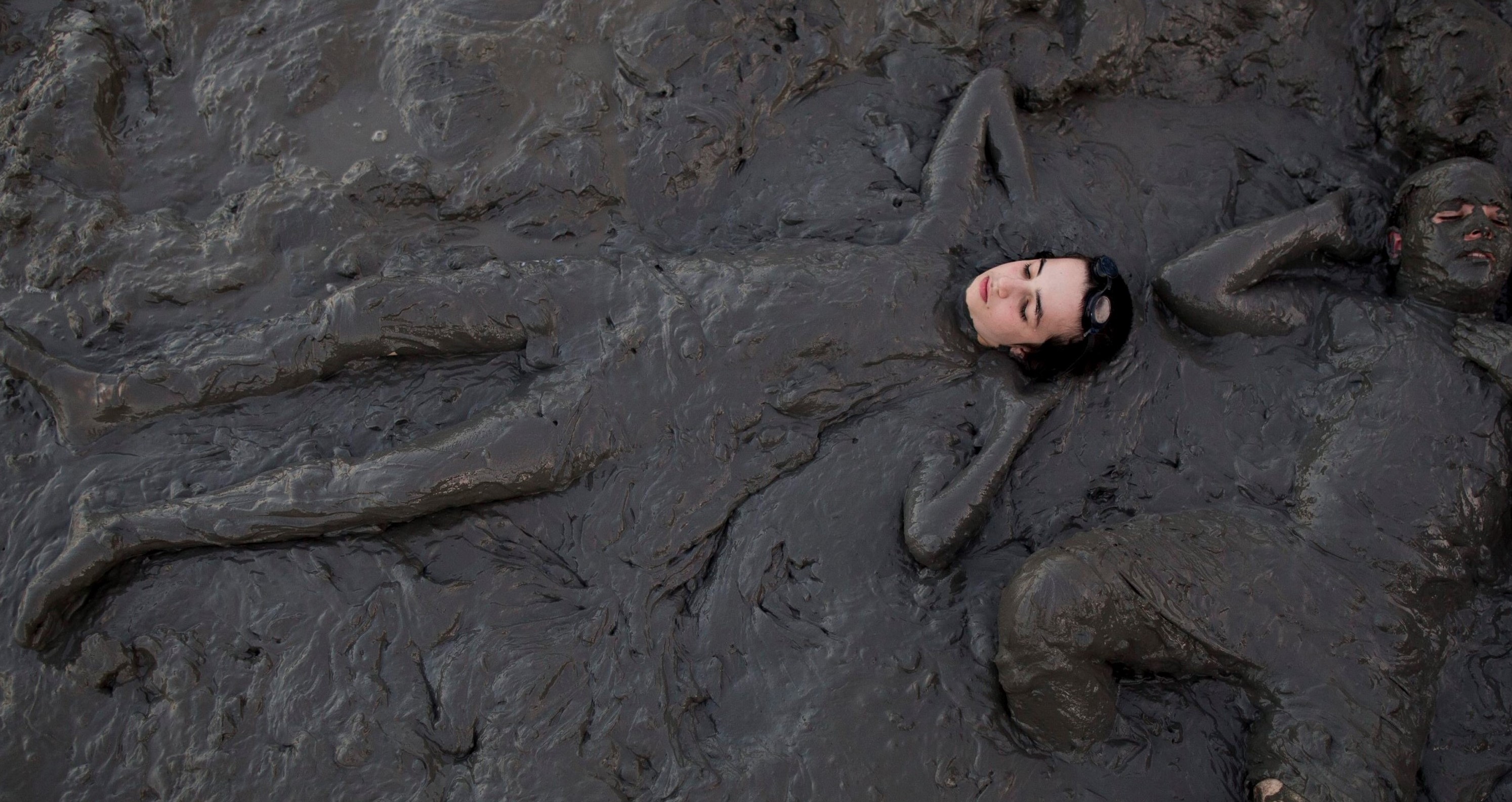 イスラエルとヨルダン国境の死海で、ミネラルを豊富に含んだ泥に包まれのんびり過ごす女性【EPA＝時事】