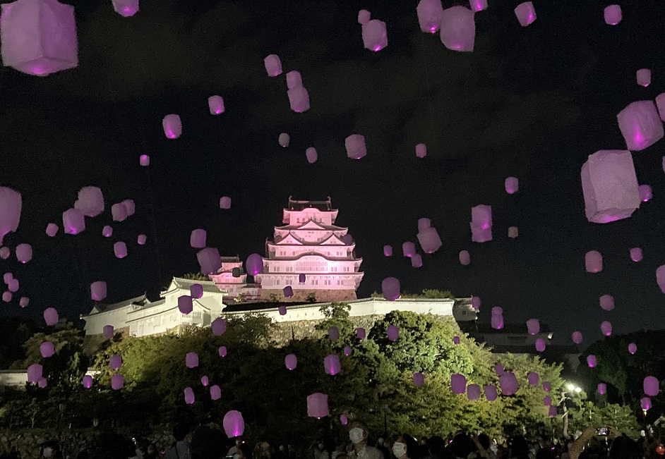 「乳がん月間」に合わせて兵庫県姫路市の世界遺産姫路城がシンボルのピンク色にライトアップされ、スカイランタンが宙を舞った= 2022年