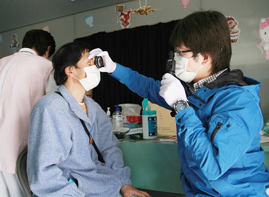 東日本大震災から約１カ月がたち、公立志津川病院の仮設診療所で、眼科の医師（右）から診察を受ける男性患者＝2011年4月15日、宮城・南三陸町