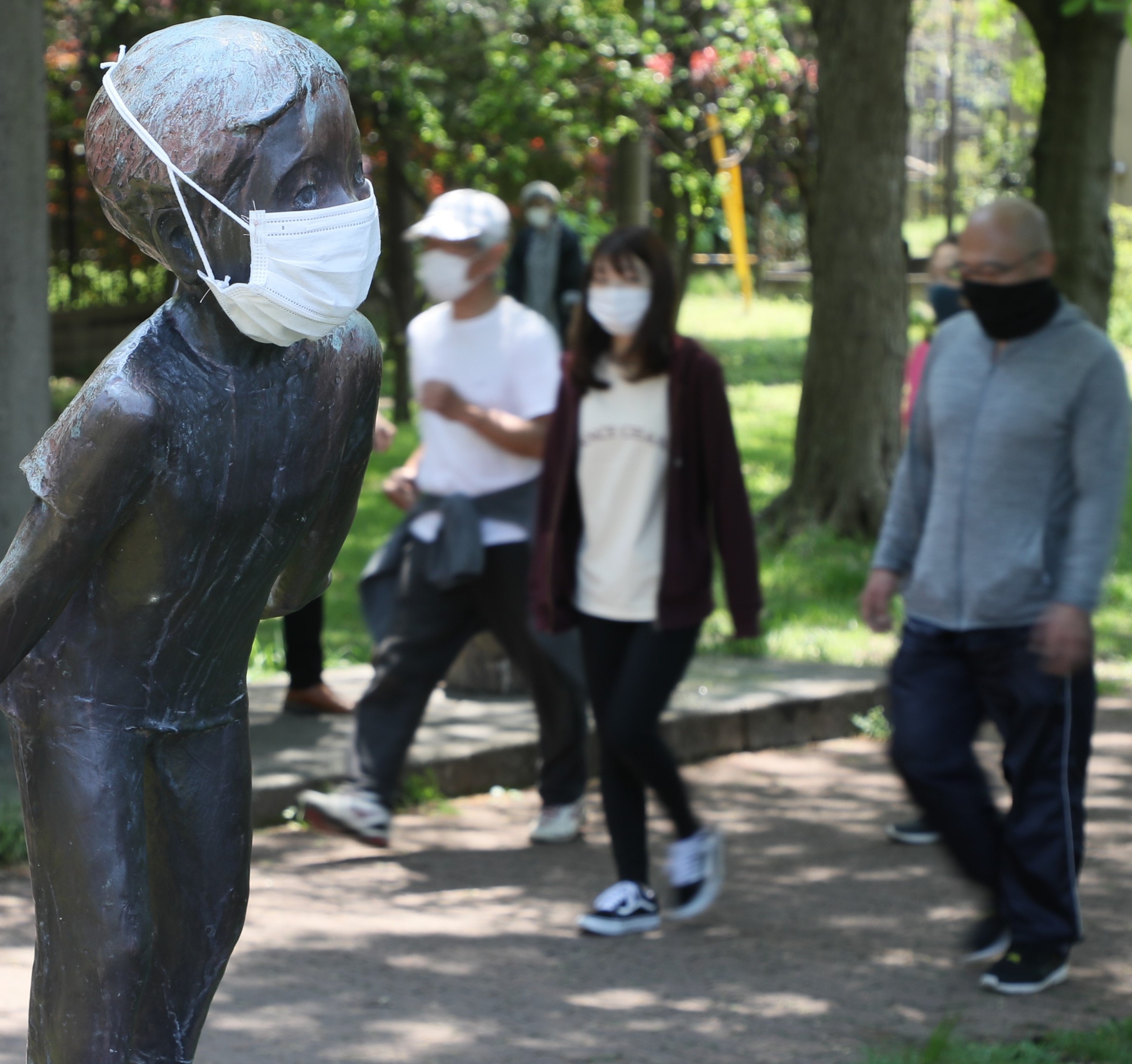 マスクを着けた像の横を散歩するマスク姿の人たち（２０２０年４月２９日撮影、東京都杉並区で）