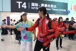 中国・杭州の空港に到着し、ボランティア（手前左）の案内を受ける日本の選手（同中央）ら＝１６日
