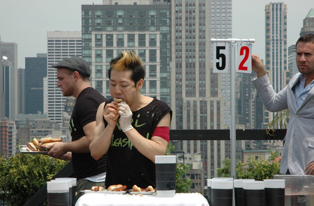 ホットドッグの早食い大会に臨む小林尊さん（中央）＝２０１１年７月、米ニューヨーク