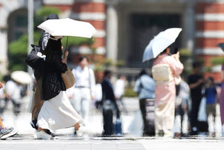 猛暑の中、日傘を差して歩く人たち＝２６日午後、東京都千代田区
