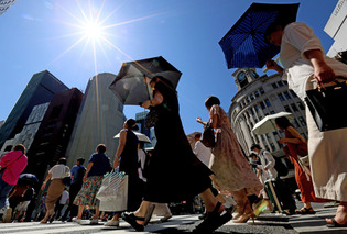 強い日差しの中、日傘を差して歩く人たち＝１６日、東京都中央区（資料写真）