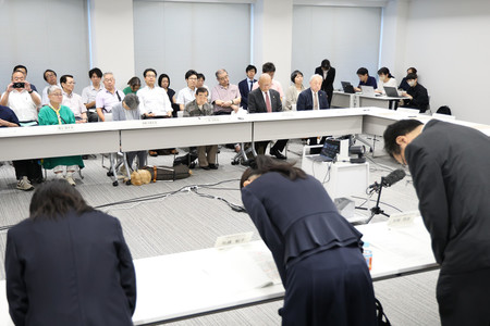 強制不妊訴訟を巡り、国と原告側の和解に向けた合意書調印式で原告ら（奥）に謝罪する加藤鮎子こども政策担当相（手前中央）＝１３日午後、東京・霞が関のこども家庭庁
