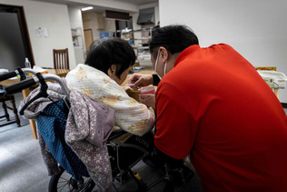 東京都内のデイケア施設で高齢の女性の世話をする介護職員（ＡＦＰ時事）（資料）