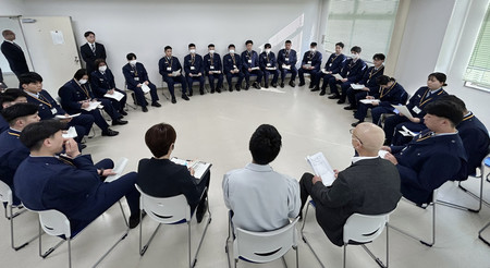 刑務官の前で自身の体験を話す「かがやきホーム」研修員の男性（手前中央）＝１月２２日、堺市
