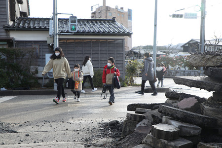 学校が再開し、保護者と登校する児童ら＝６日午前、石川県輪島市